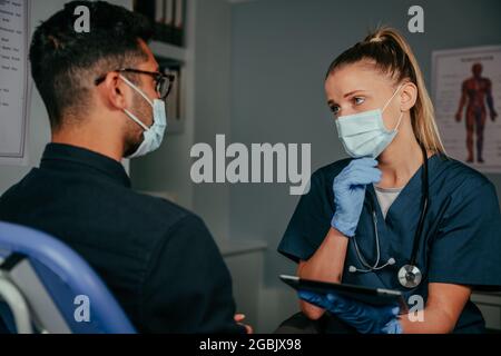 Homme de race mixte discutant avec une infirmière féminine Banque D'Images