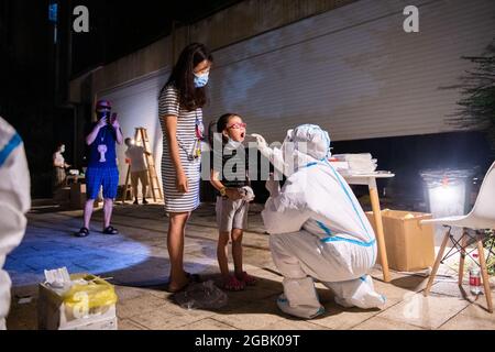 (210804) -- ZHANGJIAJIE, le 4 août 2021 (Xinhua) -- UN travailleur médical prélève un échantillon d'écouvillon d'une fille pour le test d'acide nucléique COVID-19 à Zhangjiajie, dans la province de Hunan, dans le centre de la Chine, le 4 août 2021. La ville de Zhangjiajie, dans le centre de la Chine, qui a signalé une grappe des récentes infections à COVID-19 dans le pays, avait terminé deux séries de tests d'acides nucléiques complets mardi, a déclaré les autorités locales. Plus de 809,000 personnes ont été échantillonnées depuis que la ville a lancé sa première série de tests de masse le 29 juillet, a déclaré le siège municipal sur la prévention et le contrôle de la COVID-19 lors d'une presse c Banque D'Images