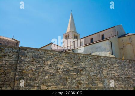 Partie des vieux murs défensifs de la ville côtière médiévale historique de Porec en Istrie, Croatie. Le clocher de la basilique euphrasienne peut être se Banque D'Images