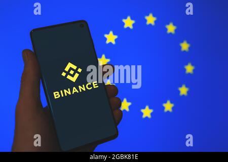 Logo de l'application Binance sur smartphone à la main avec le fond flou du drapeau de l'Union européenne. Binance en Europe, les nouvelles de la réglementation de l'UE. Échange de crypto Banque D'Images