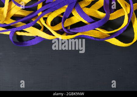 Lacets jaunes et violets, drapeau Lakers, soigneusement placé sur fond en bois noir, laissant de l'espace pour le texte publicitaire Banque D'Images