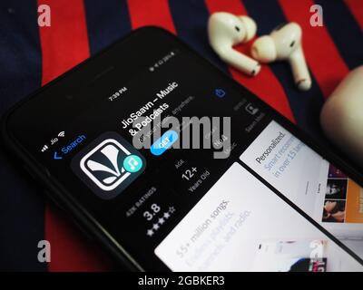 KOLKATA, INDE - 02 août 2021 : application de musique jiosaavn sur l'App Store ouverte sur l'iphone sur une table de fond coloré avec airpods pro. horiz Banque D'Images
