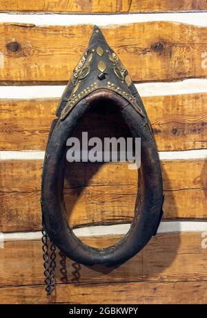 Un vieux collier de cheval est suspendu sur un mur en bois à l'intérieur de la vieille maison. Banque D'Images