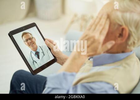 Homme aux cheveux gris lors d'une consultation en ligne avec un médecin Banque D'Images