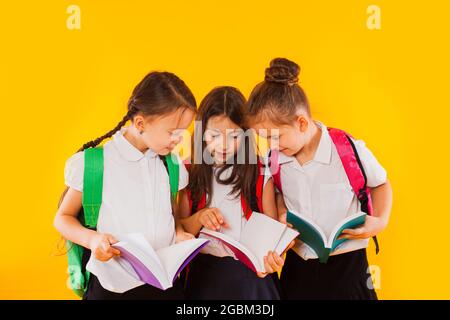 Les petites écolières lisent les livres sur fond jaune Banque D'Images