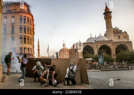 Beyrouth, Liban. 04e août 2021. Les manifestants antigouvernementaux se protègent avec des morceaux de bois lors d'affrontements avec la police anti-émeute et des soldats de l'armée libanaise à l'une des entrées du Parlement libanais après une marche pour marquer le 1er anniversaire de l'explosion massive du port de Beyrouth en août 2020. Le 04 août 2020, une grande quantité de nitrate d'ammonium entreposé dans le port de Beyrouth a été coupée, tuant au moins 218 personnes et en blessant 7,500 autres. Credit: Marwan Naamani/dpa/Alamy Live News Banque D'Images