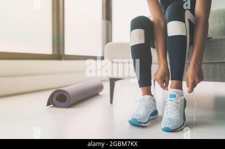 Femme attachant des lacets de chaussures de course à pied se préparer à reprendre forme en allant au yoga ou pilates entraînement de fitness à la maison Banque D'Images