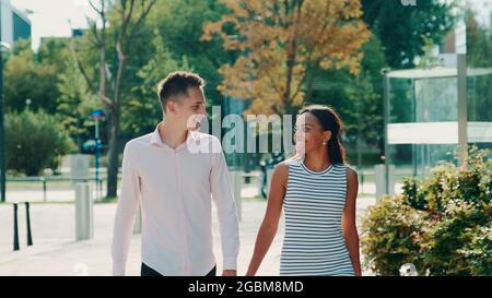Les couples multiethniques se regardent en se promenant dans la rue, en tenant les mains et en parlant. Concept de relation. Banque D'Images