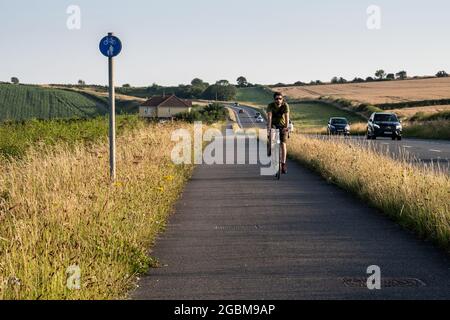 Un cycliste longe le téléphérique de Weymouth-Dorchester à côté de la route A354 dans les collines de South Dorset Downs. Banque D'Images