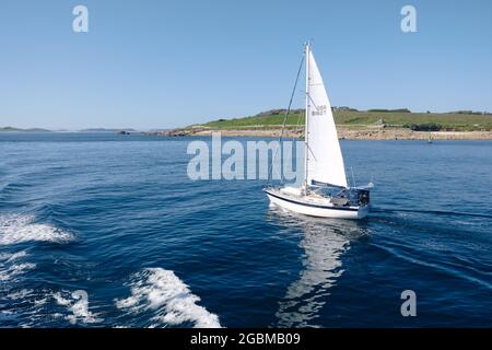 Un bateau au large de la côte de l'île de St Mary, vue depuis le ferry Scillonian III, îles de Scilly, Cornouailles, Angleterre, Royaume-Uni, Juillet 2021 Banque D'Images