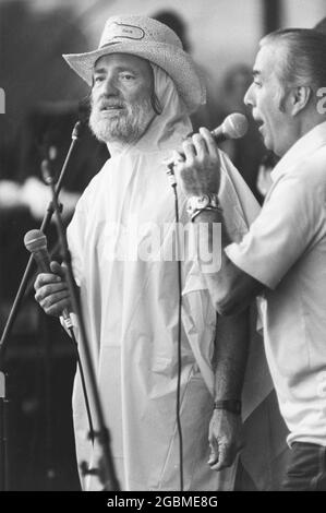 Austin, Texas, États-Unis, vers 1980 : le musicien Willie Nelson, portant un poncho de pluie. Interprète avec la chanteuse Faron Young sur scène au concert Picnic toute la journée du 4 juillet de Willie au Pedernales Country Club. ©Bob Daemmrich Banque D'Images