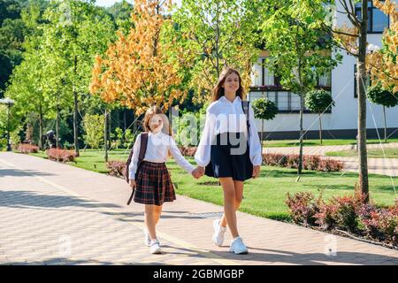 Deux sœurs filles tiennent la main et vont à l'école ensemble le matin Banque D'Images