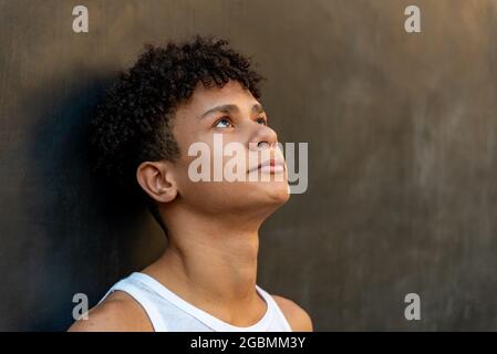 Afro latin homme adolescent contre un mur, regardant vers le haut. Banque D'Images