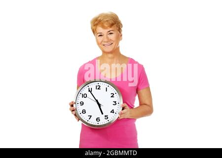 Portrait d'une vieille femme polonaise souriante tenant une grande horloge murale, isolée sur blanc Banque D'Images