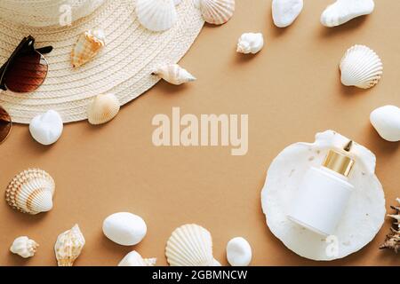 Composition de couche plate d'été avec coquillages, chapeau de paille, lunettes de soleil, crème solaire sur fond de sable Banque D'Images