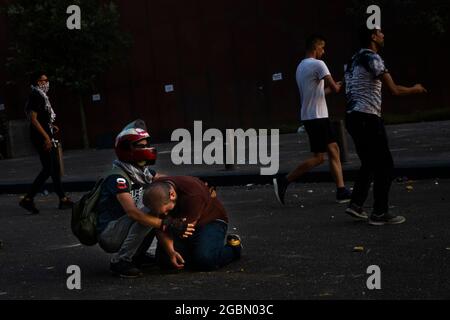 Beyrouth, Beyrouth, Liban. 4 août 2021. Un manifestant assiste un manifestant blessé lors d'une manifestation antigouvernementale à l'occasion du premier anniversaire de l'explosion portuaire de Beyrouth, au Liban, le 4 août 2021. La Croix-Rouge libanaise a signalé que 10 personnes avaient été blessées et transportées dans des hôpitaux à la suite d'affrontements dans le centre-ville de Beyrouth, et que 71 personnes avaient été soignées sur les lieux. L'explosion, l'une des plus grandes explosions non nucléaires de l'histoire humaine, a détruit des marais de la ville, tué au moins 218 personnes, blessé des milliers et déplacé environ 300,000 personnes. Un an plus et il n'y a eu aucun Banque D'Images