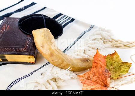 Gros plan d'une corne de shofar juive traditionnelle à côté d'un livre de prière de siddur pour Rosh Hashanah Banque D'Images