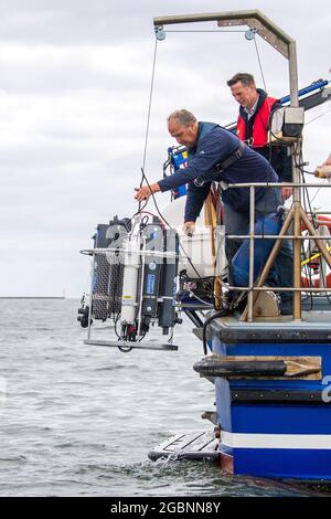 Nordsee, Allemagne. 22 juillet 2021. Helmo Nicolai (l) et Oliver Zielinski, de l'Université d'Oldenburg, abaissent un dispositif de mesure CTD du navire de recherche 'Otzum' dans l'eau. Le projet "Good Coast" des universités de Hanovre, Oldenburg et Braunschweig vise à étudier comment la protection côtière et la protection des écosystèmes peuvent être conciliées et fonctionnent également à long terme. Les chercheurs utilisent ce que l'on appelle des laboratoires réels à cette fin. Credit: Sina Schuldt/dpa/Alay Live News Banque D'Images