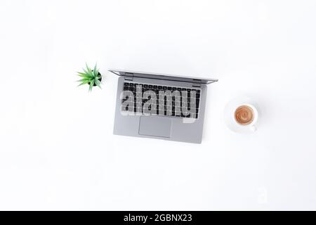 Vue de dessus sur un ordinateur portable gris fin isolé, une tasse de café expresso blanc, une cuve verte avec une plante sur fond blanc. Qual. Élevée Banque D'Images