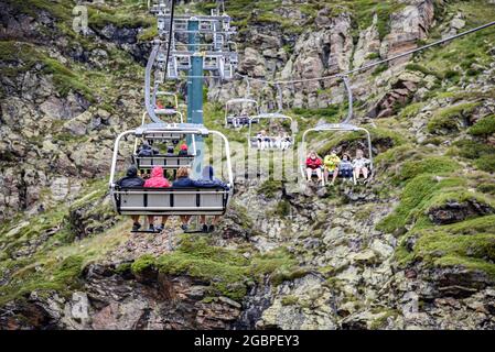 Personnes assises sur le télésiège qui accède au point de vue solaire de Tristaina en Andorre. Le Tristaina Viewpoint and Sundial est un monument en forme d'anneau qui a été inauguré au public en juillet 9 et vous permet de profiter de vues spectaculaires sur les lacs de Tristaina et la vallée d'Ordino, accessible par télésiège qu'en hiver ils sont utilisés par les skieurs et après un court trajet abrupt à pied vous atteignez sa base. Le point de vue solaire de Tristaina a été construit sur la Pico de Peyreguils, à une altitude de 2,701 m, avec vue sur la vallée d'Ordino (réserve de biosphère de l'UNESCO), à quelques kilomètres du bor Banque D'Images