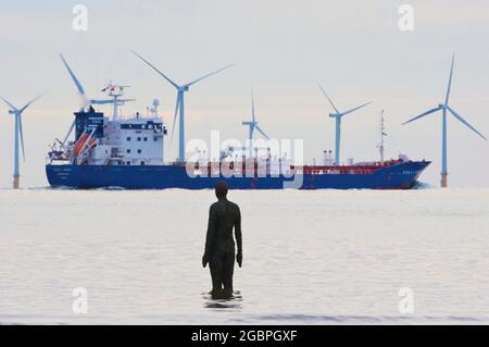 Parc éolien. Ici, nous avons divers sujets environnementaux, un parc d'éoliennes et un pétrolier avec une statue d'Anthony Gormley regardant les deux. Crosby, Liverpool. Banque D'Images