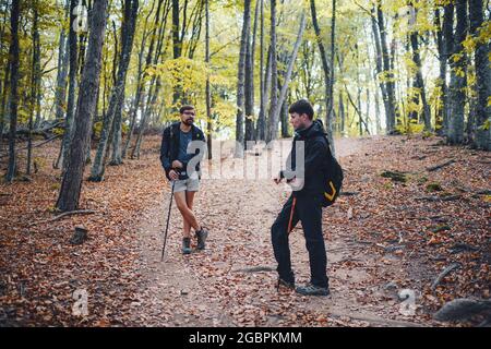 Deux hommes amis avec sac à dos randonnée ensemble dans la nature d'automne. Un routard mâle se détend et s'amuser à marcher sur le sentier de montagne. Style de vie sain en extérieur h Banque D'Images