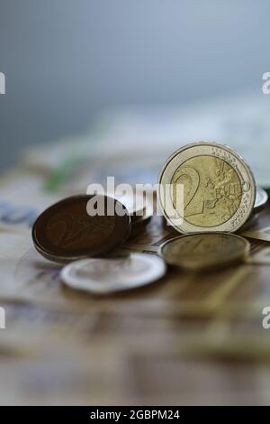 Deux pièces en euros et billets en euros sur fond vert flou. Monnaie européenne. Finances et épargne. Banque D'Images