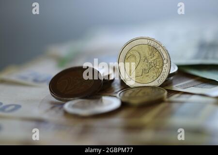 Argent. Pièces en euros et billets en euros sur fond vert flou. . Deux pièces en euros. Monnaie européenne. Finances et épargne. Banque D'Images