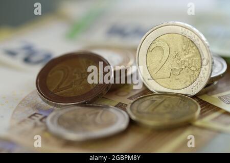 Pièces en euros et billets en euros sur fond vert flou. Deux pièces en euros. Monnaie européenne. Finances et épargne. Banque D'Images