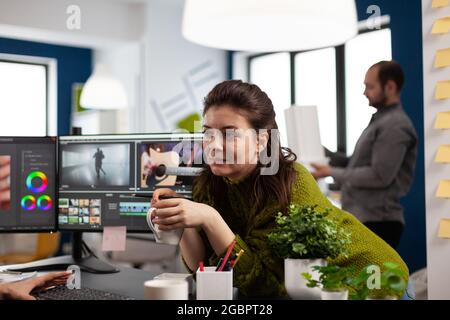 Vidéaste éditant le montage de film à l'aide de logiciels modernes partageant des idées avec un collègue dans le bureau de studio de démarrage. Collègues parlant de processus créatif dans l'agence de post-production Banque D'Images