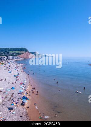 Vue panoramique sur une plage sur la côte sud de l'Angleterre lors d'une journée chaude, avec des gens qui s'amusent sur la plage et dans l'eau Banque D'Images