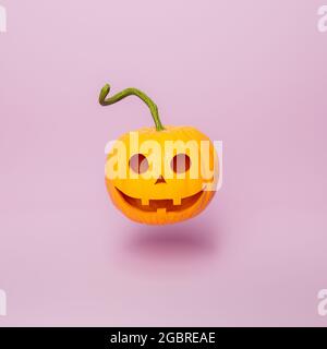 citrouille d'halloween avec visage heureux et longue tige flottant sur fond rose minimal. concept d'automne et de nuit sorcières. rendu 3d Banque D'Images