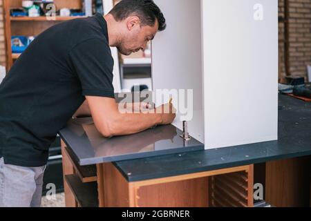 Homme marquant la surface d'une cuisine en cours de construction Banque D'Images
