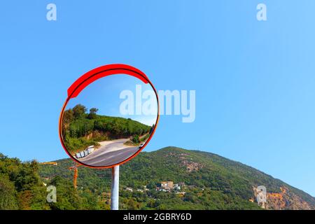 Miroir de trafic extérieur avec montagnes en arrière-plan . Miroir incurvé. Rétroviseur rond pour les angles morts sur la route Banque D'Images