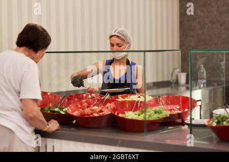 Kemer, Turquie - 24 mai 2021 : la femme masquée sert des légumes pour le buffet pour le système d'hôtel tout compris. Copier l'espace. Très bon Banque D'Images