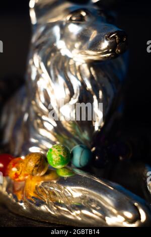 Gros plan vertical d'un bracelet avec perles texturées colorées sur une sculpture de loup argenté Banque D'Images