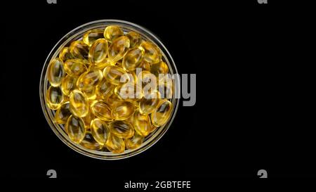Omega 3 capsules d'huile d'or sur fond noir Supplement vitamines dans les capsules de softgel. Golden Omega 3 pilules. Supplément alimentaire Banque D'Images