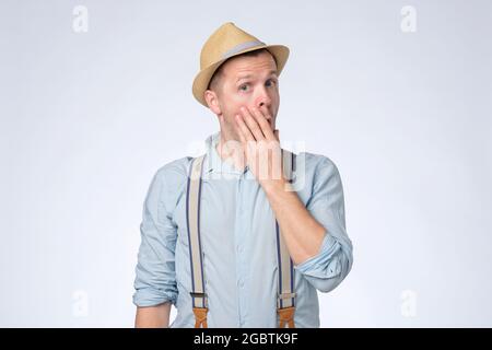Un jeune homme choqué couvrant sa bouche avec les mains. Banque D'Images
