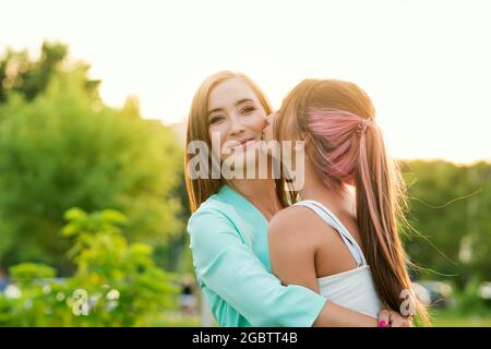 Fille de l'adolescence Kissing sur la mère souriante de joue. Profiter du moment et s'amuser ensemble. Portrait franc une adolescente et une maman méconnaissables. Banque D'Images