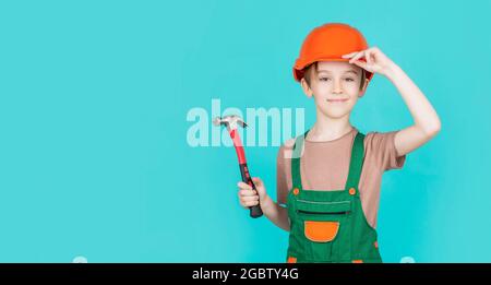 Enfant habillé comme un ouvrier de construction. Petit garçon portant un casque. Portrait petit constructeur en casque marteau. Casque de construction pour enfants, casque de chantier. Marteau Banque D'Images