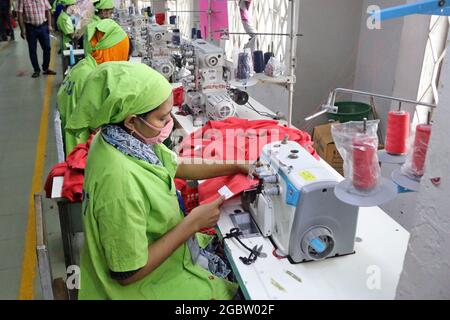 Dhaka, Bangladesh. 04e août 2021. Dhaka, Bangladesh, le 4 août 2021 : une femme porte un masque facial comme nouveau protocole de sécurité, tandis que fabrique des vêtements, après que les autorités aient autorisé la reprise des activités après une nouvelle épidémie de Covid-19. Malgré avoir atteint le plus haut sommet des cas positifs, les usines ont repris la production de vêtements pour éviter un plus grand chômage . Credit: Habibur Rahman/Eyepix Group/Alay Live News Credit: EYEPIX Group/Alay Live News Banque D'Images