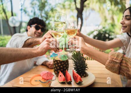 Groupe de jeunes amis qui se réunissent sur la terrasse et qui s'amusent à déguster des verres de vin blanc Banque D'Images