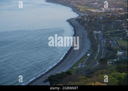 Magnifique vue aérienne en soirée sur la plage de Killiney, la ligne côtière et le chemin de fer depuis la colline de Killiney pendant l'heure d'or, Dublin, Irlande. Mise au point douce Banque D'Images