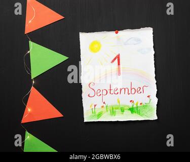 Le 1er septembre est la journée de la connaissance. Vacances, composition scolaire avec feuille blanche avec un dessin d'enfant et inspiration premier septembre, drapeaux en papier Banque D'Images