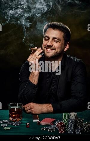 Joueur de casino barbu homme jouant au poker sur table verte Banque D'Images