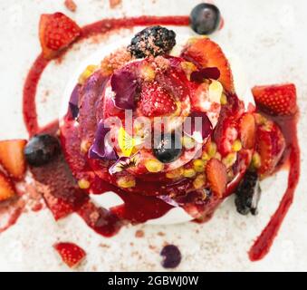 Gâteau gastronomique aux fraises Pavlova avec garniture aux baies fraîches et couches de crème fouettée et de meringue servies sur une assiette, Banque D'Images