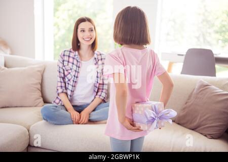 Photo de jeune femme heureuse sœur plus jeune main cadeau présent surprise anniversaire à l'intérieur de la maison Banque D'Images