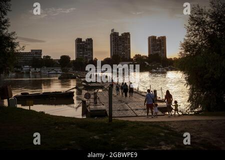 Belgrade, Serbie, 4 août 2021 : les gens traversent un pont flottant enjambant le Danube reliant l'île de la Grande Guerre et Zemun, alors que le soleil se couche. Banque D'Images