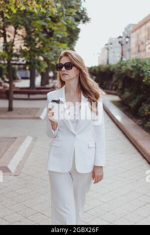 Portrait d'une femme d'affaires marchant avec une tasse de papier à l'extérieur. Matin ou à pied pendant la pause de la journée de travail. Se calmer après le travail Banque D'Images