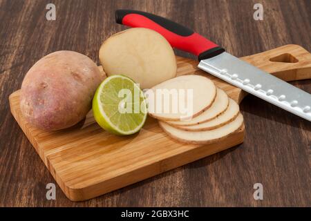 Préparation de pommes de terre en tranches avec du citron; photo sur fond de bois Banque D'Images